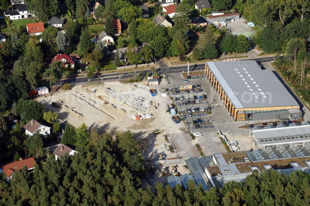 Hohen Neuendorf from the bird's eye view: Construction site of a new shopping center and store of the Supermarket REWE in Hohen Neuendorf in the state of Brandenburg. A new shopping facility with stores is being built as part of the regeneration of the shopping center HDZ on Schoenfliesser Strasse. The project is carried out by GVG Projektentwicklungsgesellschaft mbH