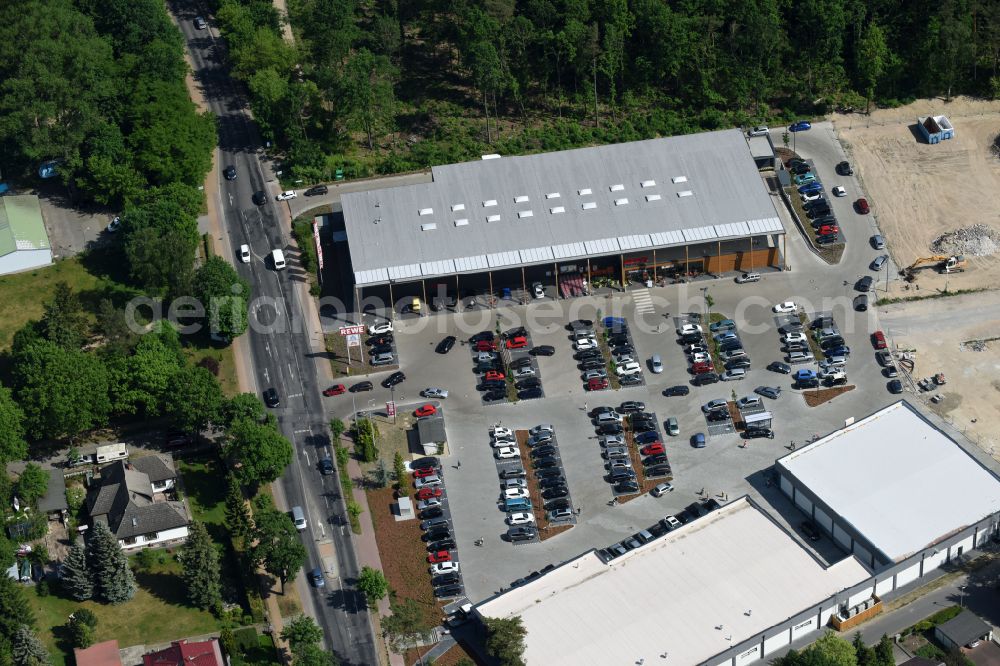 Hohen Neuendorf from above - Construction site of a new shopping center and store of the Supermarket REWE in Hohen Neuendorf in the state of Brandenburg. A new shopping facility with stores is being built as part of the regeneration of the shopping center HDZ on Schoenfliesser Strasse. The project is carried out by GVG Projektentwicklungsgesellschaft mbH