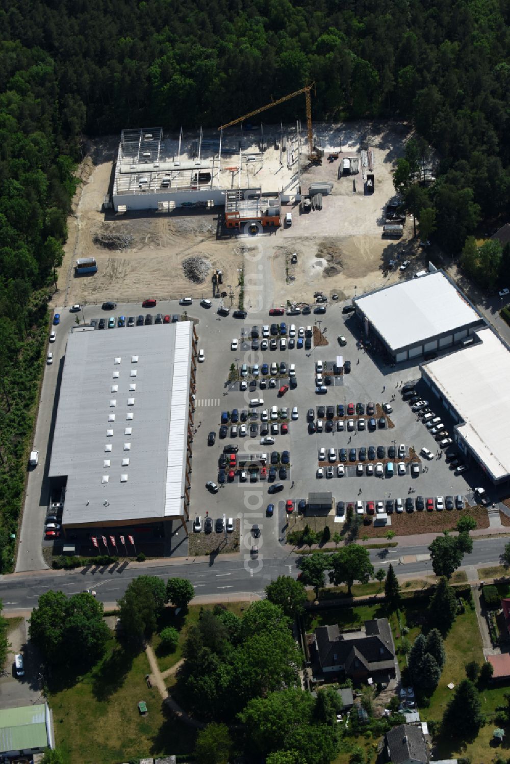 Hohen Neuendorf from the bird's eye view: Construction site of a new shopping center and store of the Supermarket REWE in Hohen Neuendorf in the state of Brandenburg. A new shopping facility with stores is being built as part of the regeneration of the shopping center HDZ on Schoenfliesser Strasse. The project is carried out by GVG Projektentwicklungsgesellschaft mbH