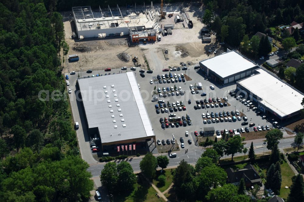 Hohen Neuendorf from the bird's eye view: Construction site of a new shopping center and store of the Supermarket REWE in Hohen Neuendorf in the state of Brandenburg. A new shopping facility with stores is being built as part of the regeneration of the shopping center HDZ on Schoenfliesser Strasse. The project is carried out by GVG Projektentwicklungsgesellschaft mbH