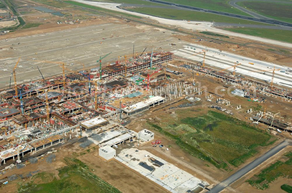 Aerial photograph Schönefeld - Blick auf die Baustelle des neuen Fern- und S-Bahnhofes der Deutschen Bahn auf der Großbaustelle Neubau Bahnhof BBI (SXF) am Flughafen Berlin - Schönefeld. Ausführende Firmen: Hochtief AG; EUROVIA Beton; PORR; BERGER Bau; Kark Weiss; Matthai; Schäler Bau Berlin GmbH; STRABAG; MAX BÖGL