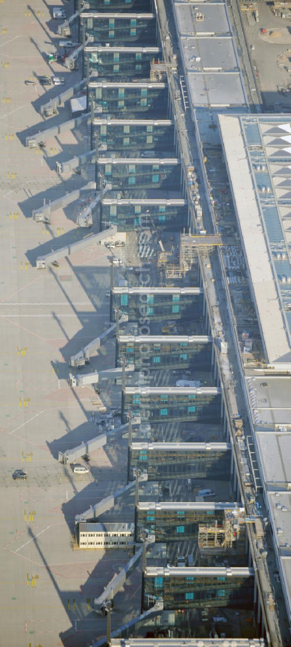 Aerial image Schönefeld - Baustelle des fast fertigen Terminals am Flughafen Schönefeld (BBI). Der neue Terminal wird südlich des jetzigen Flughafens Berlin- Schönefeld errichtet. Der Flughafen Berlin Brandenburg (IATA Code BER , ICAO Code EDDB) wird ein internationaler Verkehrsflughafen auf dem Gebiet der Gemeinde Schönefeld im Land Brandenburg. Er trägt den Beinamen Willy Brandt und soll durch die Flughafen Berlin Brandenburg GmbH betrieben werden. Beteiligte Baufirmen sind die Hochtief AG; EUROVIA Beton; PORR; BERGER Bau; Karl Weiss; Matthai; Schäler Bau Berlin GmbH; STRABAG; Construction area of the new terminal at Schönefeld Airport (BBI). The new terminal is in the south of the airport Berlin -Schoenefeld quality built. Exporting companies: Hochtief AG; EUROVIA Beton; PORR; BERGER Bau; Karl Weiss; Matthai; Schäler Bau Berlin GmbH; STRABAG;