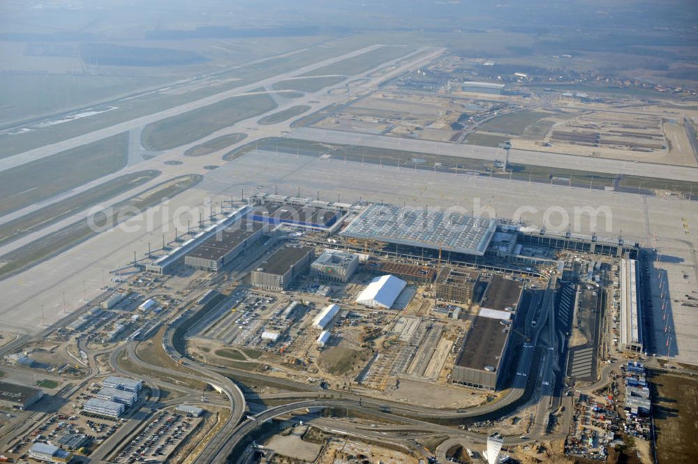 Aerial photograph Schönefeld - Baustelle des fast fertigen Terminals am Flughafen Schönefeld (BBI). Der neue Terminal wird südlich des jetzigen Flughafens Berlin- Schönefeld errichtet. Der Flughafen Berlin Brandenburg (IATA Code BER , ICAO Code EDDB) wird ein internationaler Verkehrsflughafen auf dem Gebiet der Gemeinde Schönefeld im Land Brandenburg. Er trägt den Beinamen Willy Brandt und soll durch die Flughafen Berlin Brandenburg GmbH betrieben werden. Beteiligte Baufirmen sind die Hochtief AG; EUROVIA Beton; PORR; BERGER Bau; Karl Weiss; Matthai; Schäler Bau Berlin GmbH; STRABAG; Construction area of the new terminal at Schönefeld Airport (BBI). The new terminal is in the south of the airport Berlin -Schoenefeld quality built. Exporting companies: Hochtief AG; EUROVIA Beton; PORR; BERGER Bau; Karl Weiss; Matthai; Schäler Bau Berlin GmbH; STRABAG;