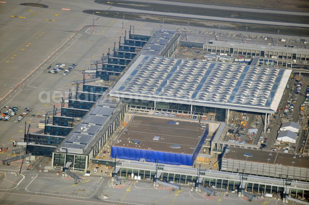 Aerial photograph Schönefeld - Baustelle des fast fertigen Terminals am Flughafen Schönefeld (BBI). Der neue Terminal wird südlich des jetzigen Flughafens Berlin- Schönefeld errichtet. Der Flughafen Berlin Brandenburg (IATA Code BER , ICAO Code EDDB) wird ein internationaler Verkehrsflughafen auf dem Gebiet der Gemeinde Schönefeld im Land Brandenburg. Er trägt den Beinamen Willy Brandt und soll durch die Flughafen Berlin Brandenburg GmbH betrieben werden. Beteiligte Baufirmen sind die Hochtief AG; EUROVIA Beton; PORR; BERGER Bau; Karl Weiss; Matthai; Schäler Bau Berlin GmbH; STRABAG; Construction area of the new terminal at Schönefeld Airport (BBI). The new terminal is in the south of the airport Berlin -Schoenefeld quality built. Exporting companies: Hochtief AG; EUROVIA Beton; PORR; BERGER Bau; Karl Weiss; Matthai; Schäler Bau Berlin GmbH; STRABAG;