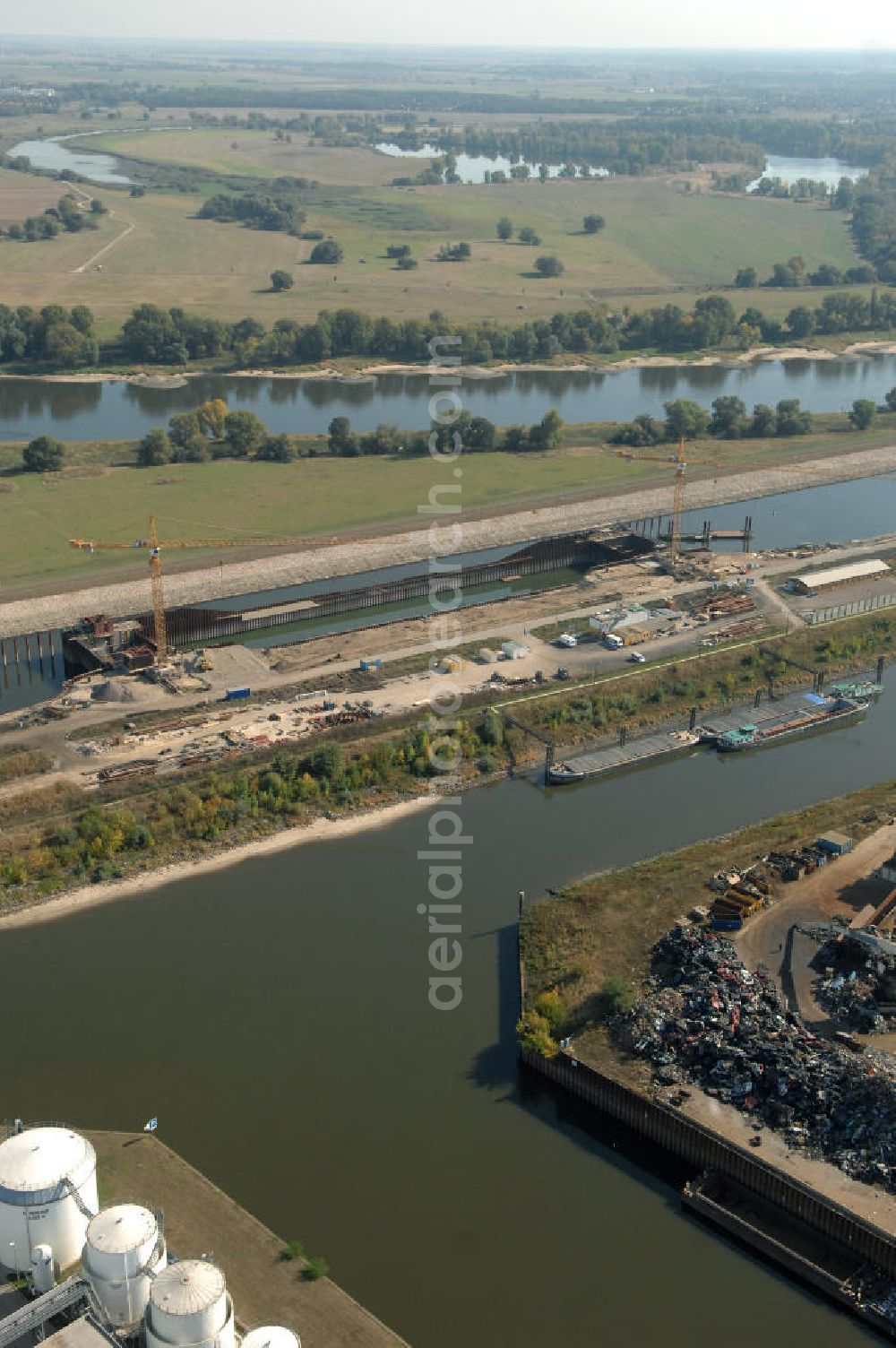 Magdeburg from above - Blick auf die Baustelle der Niedrigwasserschleuse an der Steinkopfinsel im Hafen Magdeburg an der Elbe. Umflossen wird die Steinkopfinsel im Osten von der Elbe und dem Abstiegskanal Rothensee, sowie im Westen vom Zweigkanal Magdeburg. Die Insel ist ca. 2,5 km lang und ca. 0,3 km breit (an der stärksten Stelle). Der Binnenhafen ist in vier Güterumschlagplätze eingeteilt, der Handelshafen, Industriehafen, Kanalhafen und der Hanseshafen. Das Gebiet verteilt sich über die Stadtteile Alte-Neustadt, Industriehafen und Gewerbegebiet Nord. Jedoch hat der Handelshafen für die Schiffahrt heute keine Bedeutung mehr, dieser Bereich wird stetig zum Wissenschaftsstandort umgebaut. Kontakt: Magdeburger Hafen GmbH, Saalestraße 20, 39126 Magdeburg, Tel. +49(0)391 5939-0, Fax +49(0)391 5616648, email: Logistik@magdeburg-hafen.de; Kontakt WSV: Wasserstraßen-Neubauamt Magdeburg, 39106 Magdeburg, Tel. +49(0)391 535-0, email: wna-magdeburg@wsv.bund.de