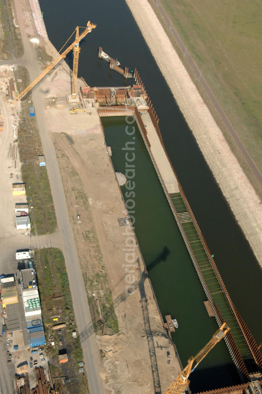 Magdeburg from above - Blick auf die Baustelle der Niedrigwasserschleuse an der Steinkopfinsel im Hafen Magdeburg an der Elbe. Umflossen wird die Steinkopfinsel im Osten von der Elbe und dem Abstiegskanal Rothensee, sowie im Westen vom Zweigkanal Magdeburg. Die Insel ist ca. 2,5 km lang und ca. 0,3 km breit (an der stärksten Stelle). Der Binnenhafen ist in vier Güterumschlagplätze eingeteilt, der Handelshafen, Industriehafen, Kanalhafen und der Hanseshafen. Das Gebiet verteilt sich über die Stadtteile Alte-Neustadt, Industriehafen und Gewerbegebiet Nord. Jedoch hat der Handelshafen für die Schiffahrt heute keine Bedeutung mehr, dieser Bereich wird stetig zum Wissenschaftsstandort umgebaut. Kontakt: Magdeburger Hafen GmbH, Saalestraße 20, 39126 Magdeburg, Tel. +49(0)391 5939-0, Fax +49(0)391 5616648, email: Logistik@magdeburg-hafen.de; Kontakt WSV: Wasserstraßen-Neubauamt Magdeburg, 39106 Magdeburg, Tel. +49(0)391 535-0, email: wna-magdeburg@wsv.bund.de