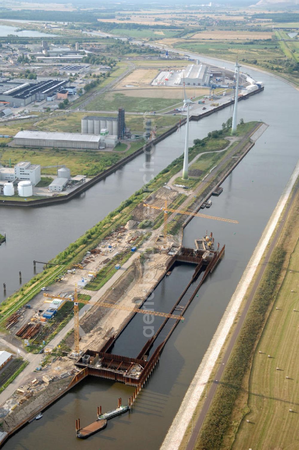 Magdeburg from above - Blick auf die Baustelle der Niedrigwasserschleuse an der Steinkopfinsel im Hafen Magdeburg an der Elbe. Umflossen wird die Steinkopfinsel im Osten von der Elbe und dem Abstiegskanal Rothensee, sowie im Westen vom Zweigkanal Magdeburg. Die Insel ist ca. 2,5 km lang und ca. 0,3 km breit (an der stärksten Stelle). Der Binnenhafen ist in vier Güterumschlagplätze eingeteilt, der Handelshafen, Industriehafen, Kanalhafen und der Hanseshafen. Das Gebiet verteilt sich über die Stadtteile Alte-Neustadt, Industriehafen und Gewerbegebiet Nord. Jedoch hat der Handelshafen für die Schiffahrt heute keine Bedeutung mehr, dieser Bereich wird stetig zum Wissenschaftsstandort umgebaut. Kontakt: Magdeburger Hafen GmbH, Saalestraße 20, 39126 Magdeburg, Tel. +49(0)391 5939-0, Fax +49(0)391 5616648, email: Logistik@magdeburg-hafen.de; Kontakt WSV: Wasserstraßen-Neubauamt Magdeburg, 39106 Magdeburg, Tel. +49(0)391 535-0, email: wna-magdeburg@wsv.bund.de