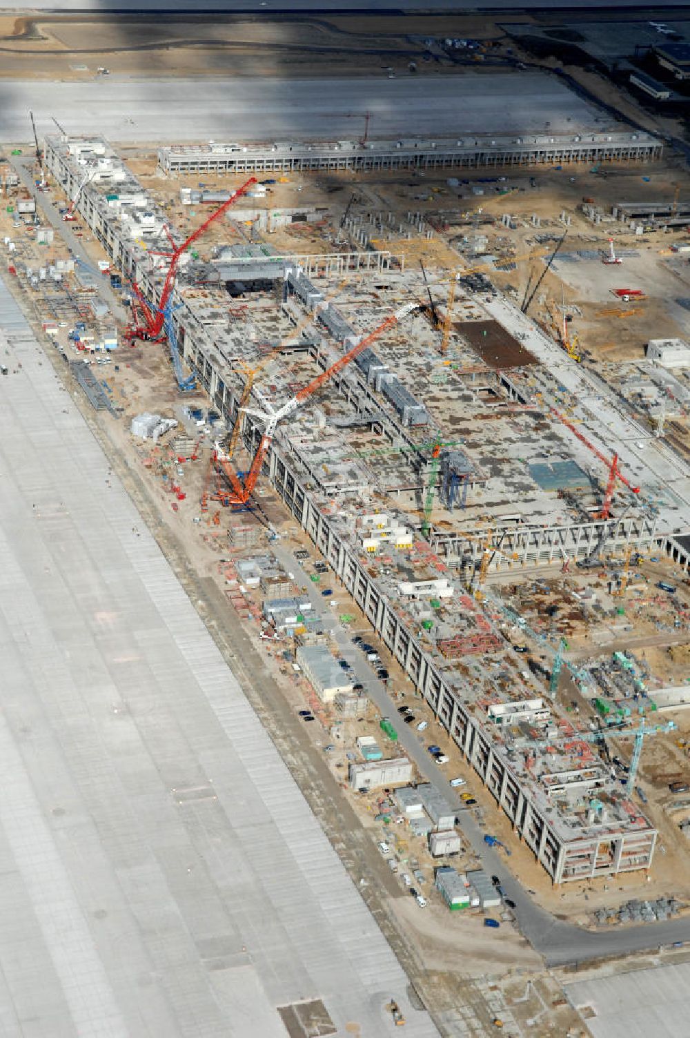 Schönefeld from the bird's eye view: Blick auf die Baustelle des neuen Fern- und S-Bahnhofes der Deutschen Bahn sowie das neue Terminal mit Vorfeld auf der Großbaustelle BBI (SXF) Flughafen Berlin-Schönefeld. Ausführende Firmen: Hochtief AG; EUROVIA Beton; PORR; BERGER Bau; Kark Weiss; Matthai; Schäler Bau Berlin GmbH; STRABAG; MAX BÖGL