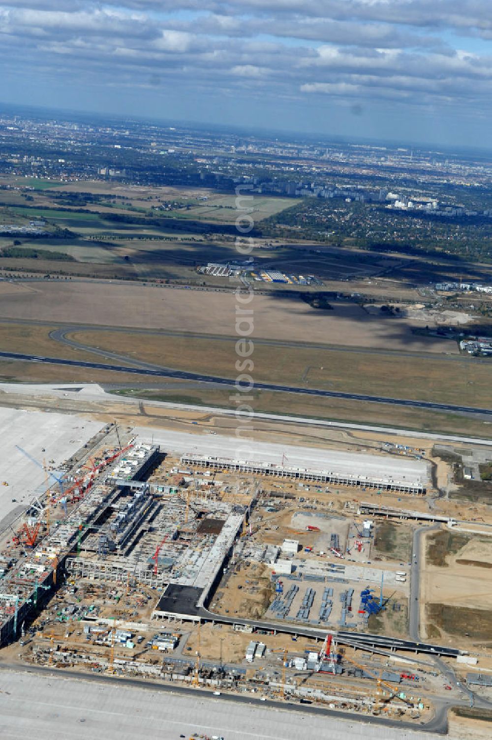 Schönefeld from the bird's eye view: Blick auf die Baustelle des neuen Fern- und S-Bahnhofes der Deutschen Bahn sowie das neue Terminal mit Vorfeld auf der Großbaustelle BBI (SXF) Flughafen Berlin-Schönefeld. Ausführende Firmen: Hochtief AG; EUROVIA Beton; PORR; BERGER Bau; Kark Weiss; Matthai; Schäler Bau Berlin GmbH; STRABAG; MAX BÖGL