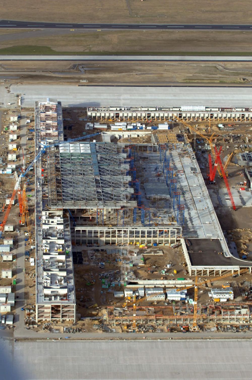 Schönefeld from the bird's eye view: Blick auf die Baustelle des neuen Fern- und S-Bahnhofes der Deutschen Bahn sowie das neue Terminal mit Vorfeld auf der Großbaustelle BBI (SXF) Flughafen Berlin-Schönefeld. Ausführende Firmen: Hochtief AG; EUROVIA Beton; PORR; BERGER Bau; Karl Weiss; Matthai; Schäler Bau Berlin GmbH; STRABAG; MAX BÖGL