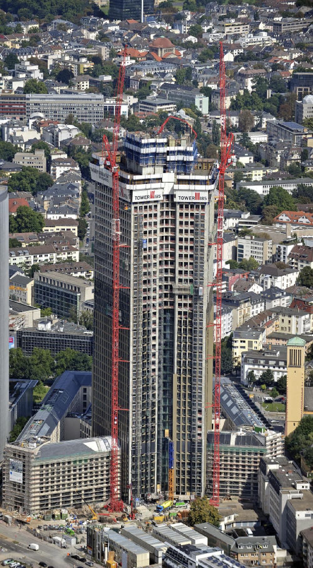 Frankfurt am Main from the bird's eye view: Blick auf die Baustelle des Tower 185 , dem derzeit höchstem, in Deutschland im Bau befindlichen Wolkenkratzer. Bauherr ist die Vivico Real Estate. Die Wirtschaftsprüfungsgesellschaft PricewaterhouseCoopers (PwC) hat bereits vor Baubeginn 60.000 Quadratmeter von insgesamt rund 90.000 Quadratmeter Bürofläche langfristig angemietet und wird hier ihre neue Deutschland-Zentrale beziehen. Den Entwurf für den Tower 185 lieferte der Frankfurter Architekt Christoph Mäckler. Er sieht ein hufeisenförmig angelegtes Sockelgebäude vor, aus dem sich die beiden Hochhaushälften mit einer Aluminium-Glas-Fassade erheben. View of the construction site of Tower 185, currently the highest skyscraper in Germany under construction. Owner is the Vivico real estate.