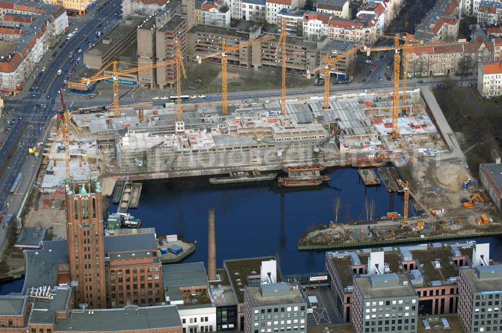 Aerial photograph Berlin - Blick auf die Baustelle vom Umbau Hafen Tempelhof am Ullsteinhaus. Der Tempelhofer Hafen entstand 1906 zusammen mit dem Teltowkanal. Zwei Jahre später kam der Speicher hinzu, eine der ersten Stahlbetonbauten in Deutschland. Im Krieg wurde das Gebäude schwer zerstört. Nach dem Wiederaufbau lagerte dort ein Teil der Lebensmittel-Reserve für West-Berlin. Bis zum Herbst 2008 sollen neben einer Einzelhandelsfläche von knapp 20 000 Quadratmetern und eine Fläche von etwa 10000 Quadratmeter für Unterhaltung, Grünflächen und Flanierwege entstehen. Hierfür wird der alte Speicher von einem Neubau flankiert. Etwa 70 Geschäfte haben in beiden Gebäuden Platz. Auf dem Dach des Neubaus entstehen 600 Parkplätze. Der Hafen selbst bleibt exklusiv Fußgängern und Freizeitkapitänen vorbehalten. Adresse: Ordensmeisterstraße, 12099 Berlin-Tempelhof; Kontakt Architekt: REM+tec Architekten, Gesellschaft für Projektentwicklung und Denkmalschutz mbH, Kurfürstenstraße 132, 10785 Berlin,Tel. 030 264767-70, Fax 030 264767-47, info@remtec.eu,