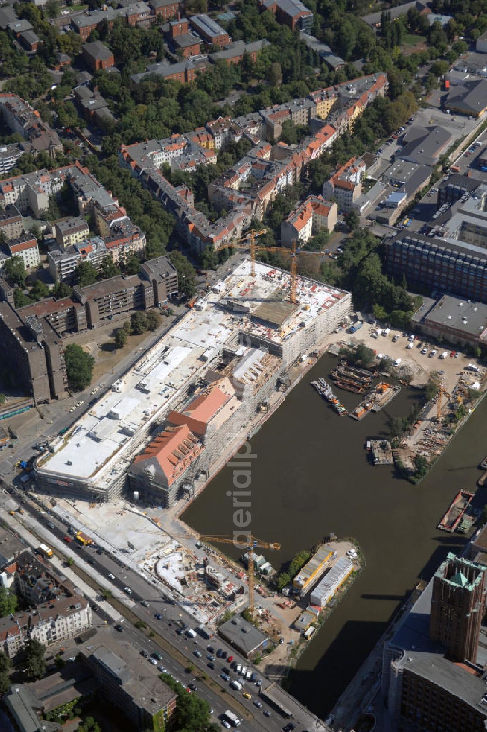 Berlin from the bird's eye view: Blick auf die Baustelle vom Umbau Hafen Tempelhof am Ullsteinhaus. Der Tempelhofer Hafen entstand 1906 zusammen mit dem Teltowkanal. Zwei Jahre später kam der Speicher hinzu, eine der ersten Stahlbetonbauten in Deutschland. Im Krieg wurde das Gebäude schwer zerstört. Nach dem Wiederaufbau lagerte dort ein Teil der Lebensmittel-Reserve für West-Berlin. Bis zum Herbst 2008 sollen neben einer Einzelhandelsfläche von knapp 20 000 Quadratmetern und eine Fläche von etwa 10000 Quadratmeter für Unterhaltung, Grünflächen und Flanierwege entstehen. Hierfür wird der alte Speicher von einem Neubau flankiert. Etwa 70 Geschäfte haben in beiden Gebäuden Platz. Auf dem Dach des Neubaus entstehen 600 Parkplätze. Der Hafen selbst bleibt exklusiv Fußgängern und Freizeitkapitänen vorbehalten. Adresse: Ordensmeisterstraße, 12099 Berlin-Tempelhof; Kontakt Architekt: REM+tec Architekten, Gesellschaft für Projektentwicklung und Denkmalschutz mbH, Kurfürstenstraße 132, 10785 Berlin,Tel. 030 264767-70, Fax 030 264767-47, info@remtec.eu,