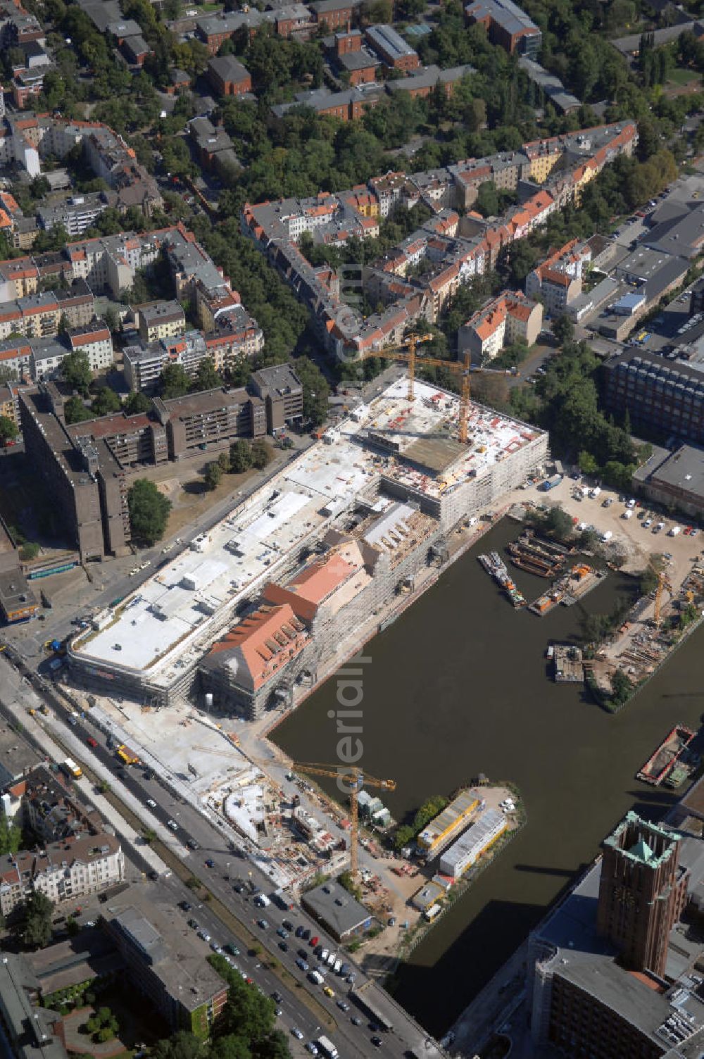 Aerial image Berlin - Blick auf die Baustelle vom Umbau Hafen Tempelhof am Ullsteinhaus. Der Tempelhofer Hafen entstand 1906 zusammen mit dem Teltowkanal. Zwei Jahre später kam der Speicher hinzu, eine der ersten Stahlbetonbauten in Deutschland. Im Krieg wurde das Gebäude schwer zerstört. Nach dem Wiederaufbau lagerte dort ein Teil der Lebensmittel-Reserve für West-Berlin. Bis zum Herbst 2008 sollen neben einer Einzelhandelsfläche von knapp 20 000 Quadratmetern und eine Fläche von etwa 10000 Quadratmeter für Unterhaltung, Grünflächen und Flanierwege entstehen. Hierfür wird der alte Speicher von einem Neubau flankiert. Etwa 70 Geschäfte haben in beiden Gebäuden Platz. Auf dem Dach des Neubaus entstehen 600 Parkplätze. Der Hafen selbst bleibt exklusiv Fußgängern und Freizeitkapitänen vorbehalten. Adresse: Ordensmeisterstraße, 12099 Berlin-Tempelhof; Kontakt Architekt: REM+tec Architekten, Gesellschaft für Projektentwicklung und Denkmalschutz mbH, Kurfürstenstraße 132, 10785 Berlin,Tel. 030 264767-70, Fax 030 264767-47, info@remtec.eu,