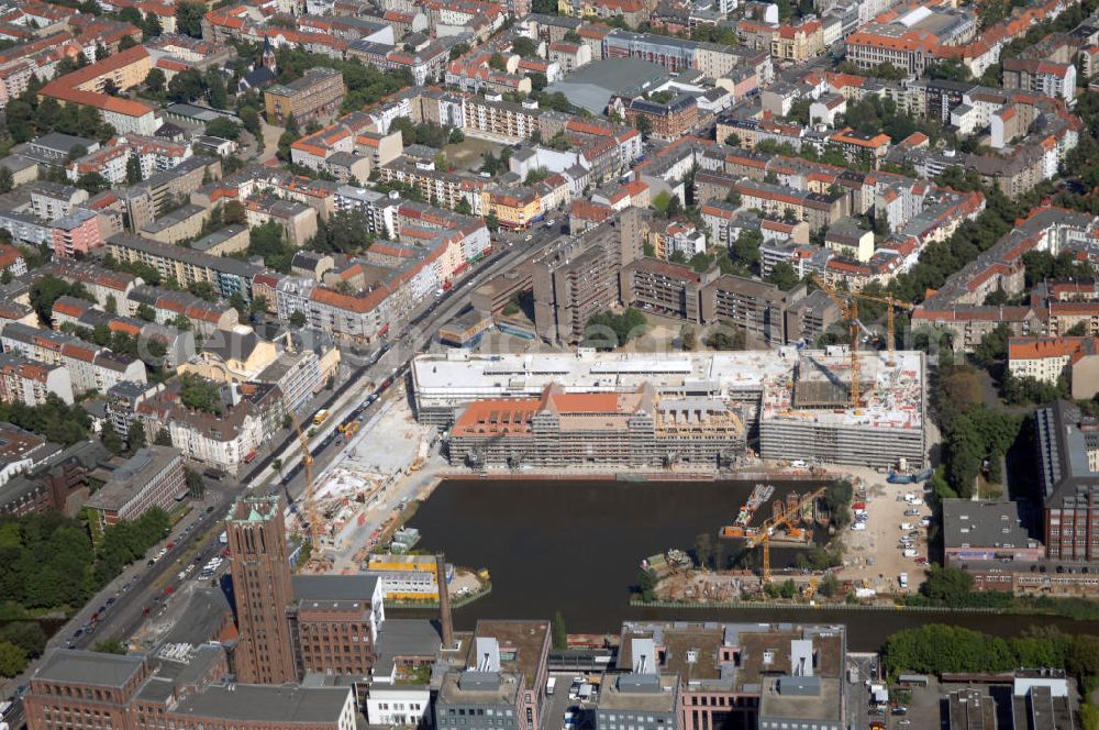 Aerial image Berlin - Blick auf die Baustelle vom Umbau Hafen Tempelhof am Ullsteinhaus. Der Tempelhofer Hafen entstand 1906 zusammen mit dem Teltowkanal. Zwei Jahre später kam der Speicher hinzu, eine der ersten Stahlbetonbauten in Deutschland. Im Krieg wurde das Gebäude schwer zerstört. Nach dem Wiederaufbau lagerte dort ein Teil der Lebensmittel-Reserve für West-Berlin. Bis zum Herbst 2008 sollen neben einer Einzelhandelsfläche von knapp 20 000 Quadratmetern und eine Fläche von etwa 10000 Quadratmeter für Unterhaltung, Grünflächen und Flanierwege entstehen. Hierfür wird der alte Speicher von einem Neubau flankiert. Etwa 70 Geschäfte haben in beiden Gebäuden Platz. Auf dem Dach des Neubaus entstehen 600 Parkplätze. Der Hafen selbst bleibt exklusiv Fußgängern und Freizeitkapitänen vorbehalten. Adresse: Ordensmeisterstraße, 12099 Berlin-Tempelhof; Kontakt Architekt: REM+tec Architekten, Gesellschaft für Projektentwicklung und Denkmalschutz mbH, Kurfürstenstraße 132, 10785 Berlin,Tel. 030 264767-70, Fax 030 264767-47, info@remtec.eu,