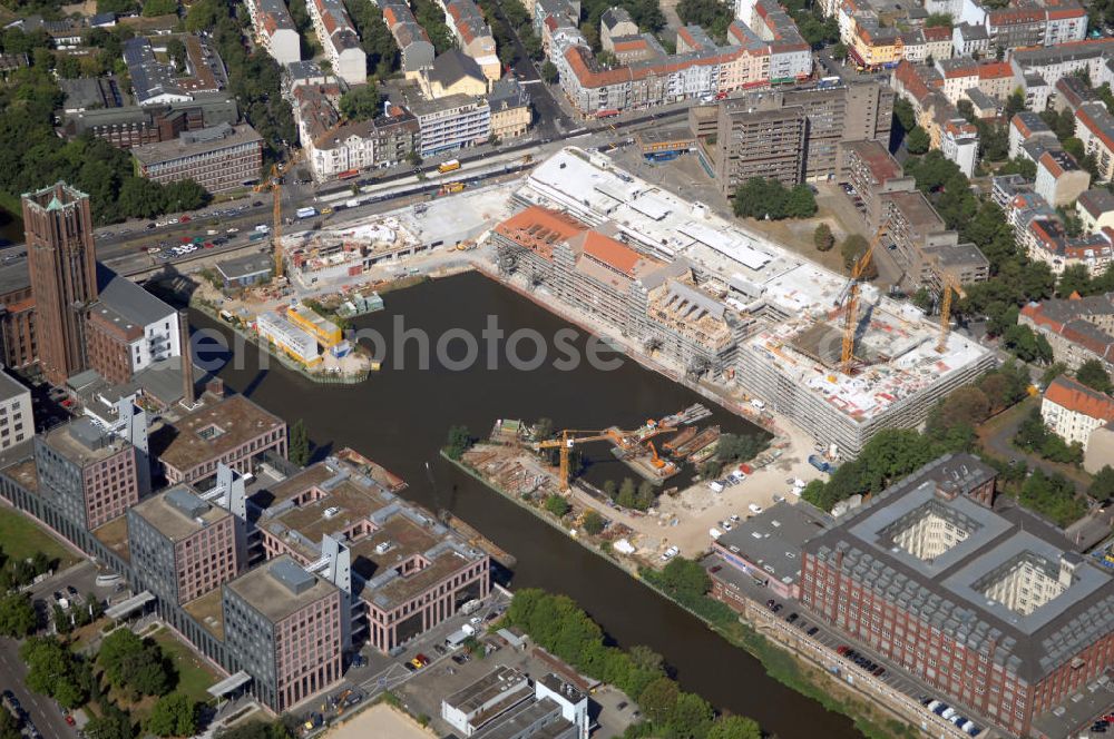 Berlin from above - Blick auf die Baustelle vom Umbau Hafen Tempelhof am Ullsteinhaus. Der Tempelhofer Hafen entstand 1906 zusammen mit dem Teltowkanal. Zwei Jahre später kam der Speicher hinzu, eine der ersten Stahlbetonbauten in Deutschland. Im Krieg wurde das Gebäude schwer zerstört. Nach dem Wiederaufbau lagerte dort ein Teil der Lebensmittel-Reserve für West-Berlin. Bis zum Herbst 2008 sollen neben einer Einzelhandelsfläche von knapp 20 000 Quadratmetern und eine Fläche von etwa 10000 Quadratmeter für Unterhaltung, Grünflächen und Flanierwege entstehen. Hierfür wird der alte Speicher von einem Neubau flankiert. Etwa 70 Geschäfte haben in beiden Gebäuden Platz. Auf dem Dach des Neubaus entstehen 600 Parkplätze. Der Hafen selbst bleibt exklusiv Fußgängern und Freizeitkapitänen vorbehalten. Adresse: Ordensmeisterstraße, 12099 Berlin-Tempelhof; Kontakt Architekt: REM+tec Architekten, Gesellschaft für Projektentwicklung und Denkmalschutz mbH, Kurfürstenstraße 132, 10785 Berlin,Tel. 030 264767-70, Fax 030 264767-47, info@remtec.eu,