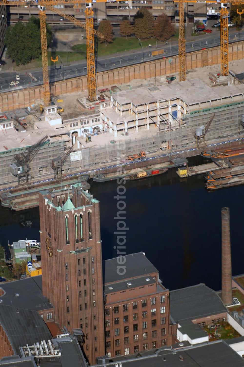 Berlin from the bird's eye view: Blick auf die Baustelle vom Umbau Hafen Tempelhof am Ullsteinhaus. Der Tempelhofer Hafen entstand 1906 zusammen mit dem Teltowkanal. Zwei Jahre später kam der Speicher hinzu, eine der ersten Stahlbetonbauten in Deutschland. Im Krieg wurde das Gebäude schwer zerstört. Nach dem Wiederaufbau lagerte dort ein Teil der Lebensmittel-Reserve für West-Berlin. Bis zum Herbst 2008 sollen neben einer Einzelhandelsfläche von knapp 20 000 Quadratmetern und eine Fläche von etwa 10000 Quadratmeter für Unterhaltung, Grünflächen und Flanierwege entstehen. Hierfür wird der alte Speicher von einem Neubau flankiert. Etwa 70 Geschäfte haben in beiden Gebäuden Platz. Auf dem Dach des Neubaus entstehen 600 Parkplätze. Der Hafen selbst bleibt exklusiv Fußgängern und Freizeitkapitänen vorbehalten. Adresse: Ordensmeisterstraße, 12099 Berlin-Tempelhof; Kontakt Architekt: REM+tec Architekten, Gesellschaft für Projektentwicklung und Denkmalschutz mbH, Kurfürstenstraße 132, 10785 Berlin,Tel. 030 264767-70, Fax 030 264767-47, info@remtec.eu,