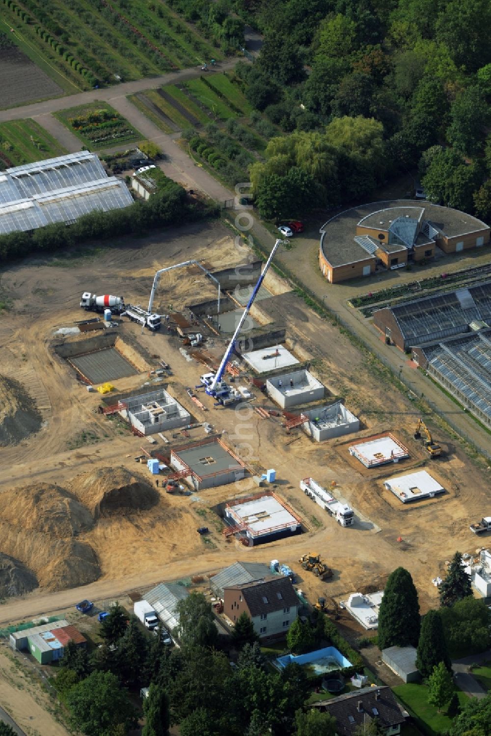 Aerial image Berlin - Construction site of a single family and semi-detached house settlement on Mohriner Allee of the Britz part of Berlin in Germany. The compound will include single family houses and residential buildings of different sizes. The compound is located next to the architectural distinct Pflanzenschutzamt (plant protection office of Berlin)