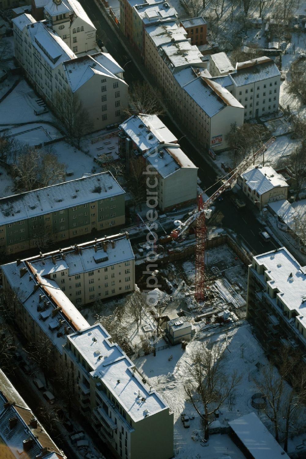 Berlin from the bird's eye view: Winterly snowy construction site to build a new multi-family residential complex besides the roads Giselastrasse and Lueckstrasse in the district Lichtenberg in Berlin in Germany