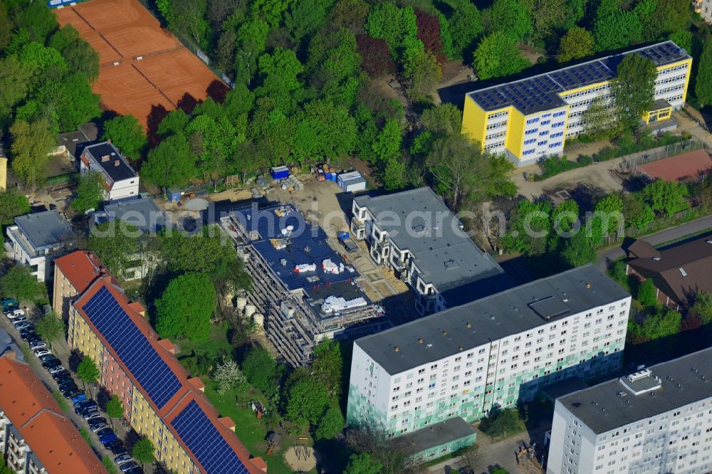 Aerial photograph Berlin - Construction site to build a new multi-family residential complex Wohnen am Gutspark in the Lichtenberg district of Berlin in Germany. A modern appartement building complex is being built between the primary school and the local tennis club in Bornitzstrasse. The four buildings are surrounded by trees and forest