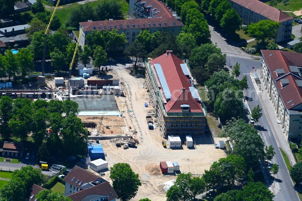 Hennigsdorf from the bird's eye view: Construction for the new building of the spa and swimming pool at the swimming pool of Recreation on Rathenaustrasse overlooking the renovation work at the building of the local start-up center in Hennigsdorf in the state Brandenburg, Germany