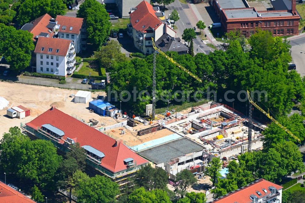 Hennigsdorf from the bird's eye view: Construction for the new building of the spa and swimming pool at the swimming pool of Recreation on Rathenaustrasse overlooking the renovation work at the building of the local start-up center in Hennigsdorf in the state Brandenburg, Germany