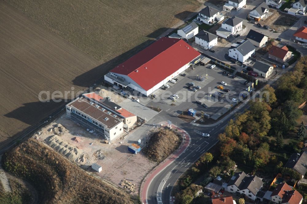 Aerial image Gau-Bischofsheim - New construction site for the construction of a kindergarten building and Nursery school next to an Edeka food market, (red roof) in Gau-Bischofsheim in the state Rhineland-Palatinate, Germany