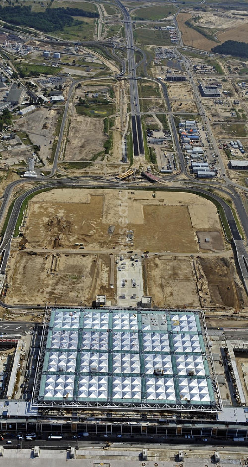 Aerial photograph Schönefeld - Blick auf die Baustellen am Flughafen Berlin-Schönefeld BBI (SXF). Ausführende Firmen: Hochtief AG; EUROVIA Beton; PORR; BERGER Bau; Karl Weiss; Matthai; Schäler Bau Berlin GmbH; STRABAG; MAX BÖGL. Construction fields at Berlin-Schoenefeld Airport BBI.