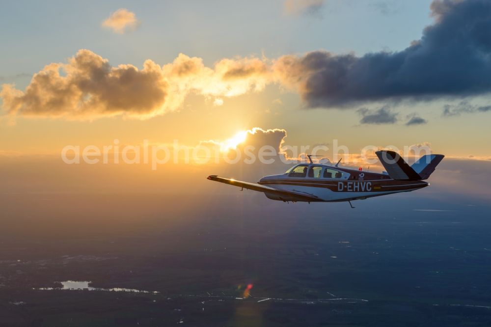 Geestland from above - Beechcraft Bonanza D-EHVC in flight while sunet near Geestland in the state of Bremen, Germany. The Beechcraft Bonanza is produced by Beech Aircraft Corporation as a travel and business aircraft