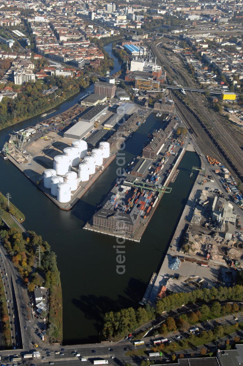 Berlin from above - Der Berliner Westhafen ist ein Binnenhafen im Ortsteil Moabit des Bezirks Mitte. Der Westhafen ist mit einer Fläche von 430.000 m² der größte Hafen der Stadt und ein bedeutender Umschlag- und Lagerplatz für die Binnenschifffahrt. Die Berliner Hafen-und Lagerhausgesellschaft mbH, kurz BEHALA genannt, betreibt in Berlin mehrere Binnenhäfen mit den dazugehörigen Lagerhäusern, dem Güterumschlag, einer Bauschuttentsorgung, den Hafenbahnen, und die Vermietung von Immobilien auf den Hafengeländen. Sie ist ein Eigenbetrieb der Stadt Berlin. Weitere Informationen unter