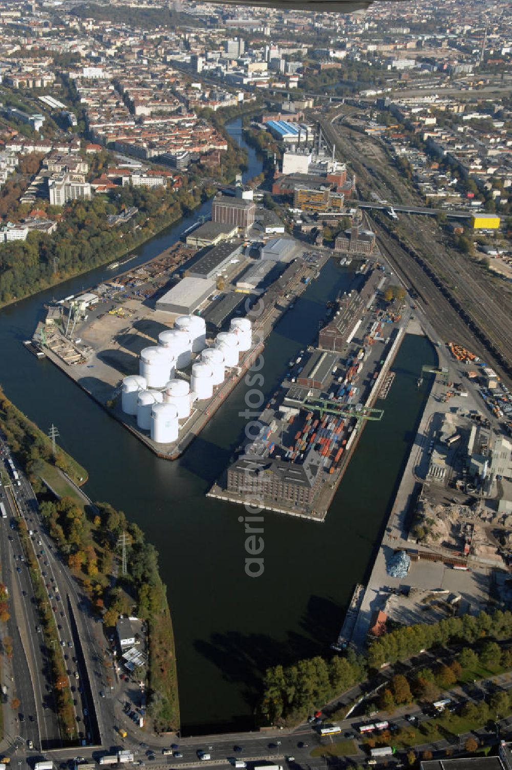 Berlin from the bird's eye view: Der Berliner Westhafen ist ein Binnenhafen im Ortsteil Moabit des Bezirks Mitte. Der Westhafen ist mit einer Fläche von 430.000 m² der größte Hafen der Stadt und ein bedeutender Umschlag- und Lagerplatz für die Binnenschifffahrt. Die Berliner Hafen-und Lagerhausgesellschaft mbH, kurz BEHALA genannt, betreibt in Berlin mehrere Binnenhäfen mit den dazugehörigen Lagerhäusern, dem Güterumschlag, einer Bauschuttentsorgung, den Hafenbahnen, und die Vermietung von Immobilien auf den Hafengeländen. Sie ist ein Eigenbetrieb der Stadt Berlin. Weitere Informationen unter