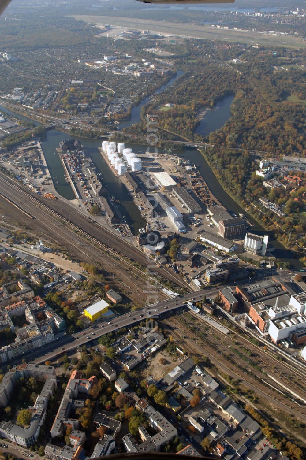 Berlin from above - Der Berliner Westhafen ist ein Binnenhafen im Ortsteil Moabit des Bezirks Mitte. Der Westhafen ist mit einer Fläche von 430.000 m² der größte Hafen der Stadt und ein bedeutender Umschlag- und Lagerplatz für die Binnenschifffahrt. Die Berliner Hafen-und Lagerhausgesellschaft mbH, kurz BEHALA genannt, betreibt in Berlin mehrere Binnenhäfen mit den dazugehörigen Lagerhäusern, dem Güterumschlag, einer Bauschuttentsorgung, den Hafenbahnen, und die Vermietung von Immobilien auf den Hafengeländen. Sie ist ein Eigenbetrieb der Stadt Berlin. Weitere Informationen unter