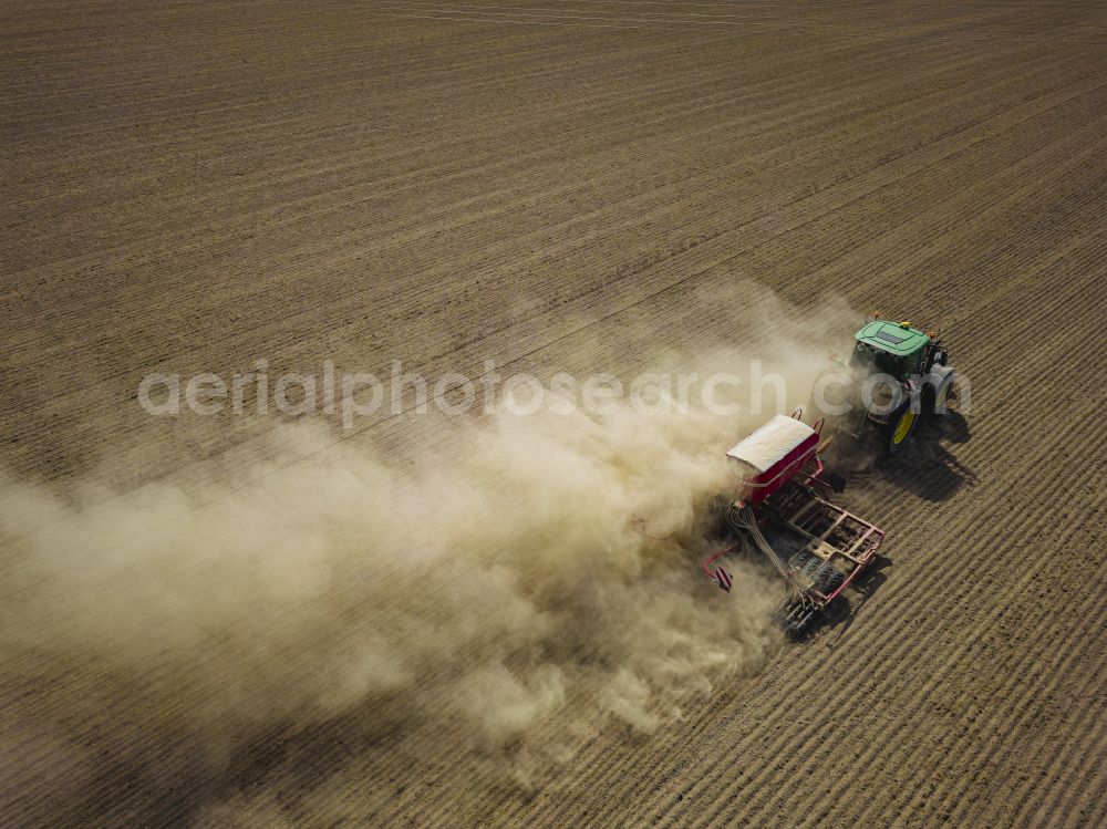 Dohma from the bird's eye view: Cultivation of a field using a tractor with agricultural machine for sowing on street Am Kirschberg in Dohma in the state Saxony, Germany