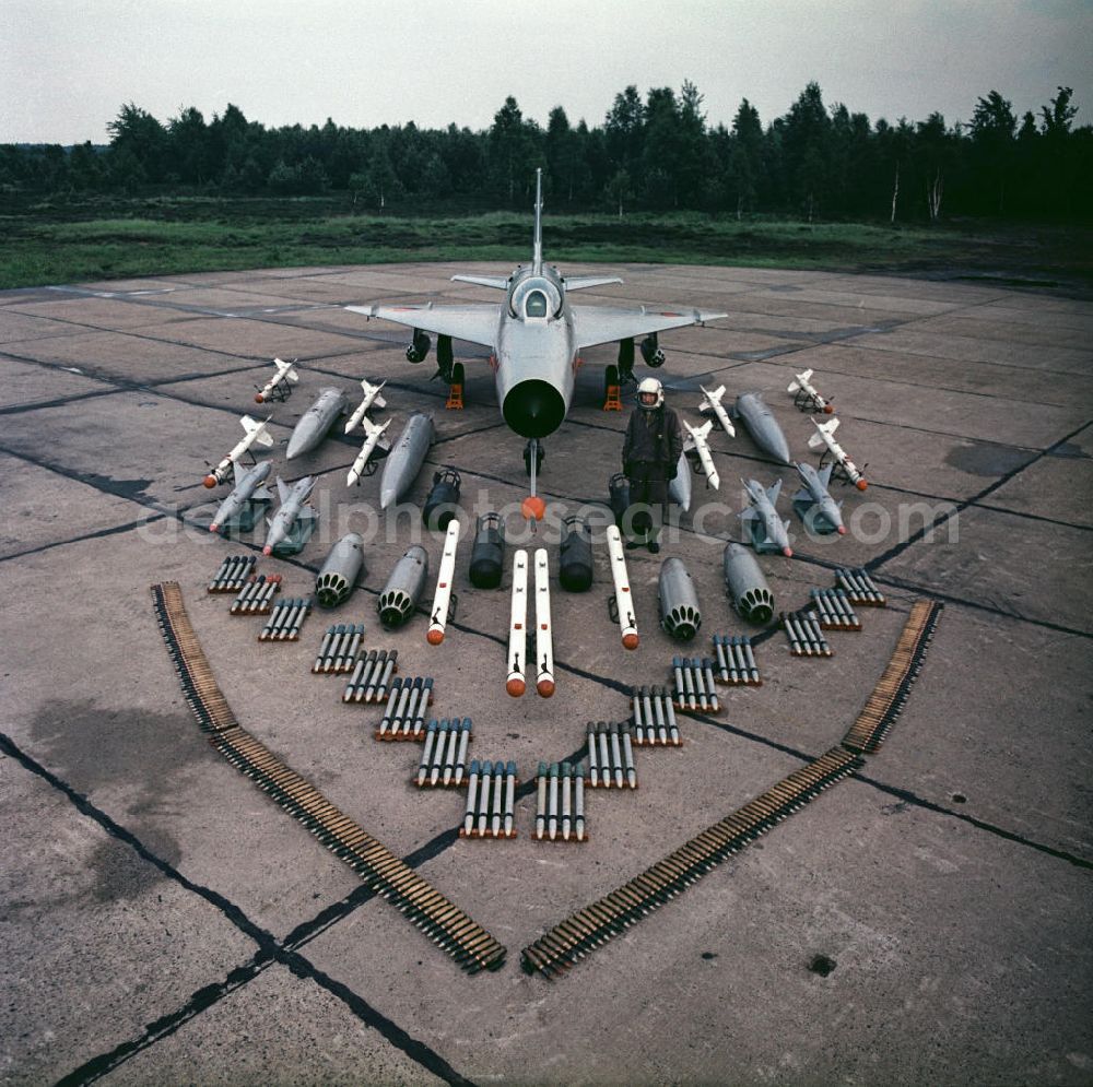 Drewitz from above - Blick auf die Bewaffnung einer Mikojan-Gurewitsch MiG-21 neben einem Jagdflieger / Piloten der NVA auf dem Flugplatz Cottbus-Drewitz. Der Abfangjäger MiG-21 ist das seit dem Zweiten Weltkrieg meistgebaute Kampfflugzeug der Welt. View of the arming of a Mikoyan-Gurevich MiG-21 next to a fighter pilot of the NVA. The interceptor MiG-21 is the most built fighter aircraft since the Second World War.