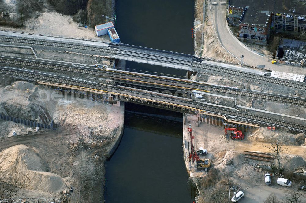 Aerial photograph Berlin - Blick auf den Um- und Ausbau des S-Bahnhofes Berlin-Baumschulenweg.Die Fassade des Haupteinganges auf der Ostseite, die der Bahnhof 1916 erhielt und die heute unter Denkmalschutz steht, bleibt dabei erhalten. Ansonsten wird der erneuerungsbedürftige Bahnhof künftig modernen Ansprüchen an Komfort, Sicherheit, Gestaltung und Leistungsfähigkeit gerecht. Rund 28 Millionen Euro werden investiert.Die Brücken der drei S-Bahn- und zwei Fernbahngleise werden neu gebaut. Die Breite der Baumschulenstraße bleibt erhalten, ebenso die auf 3,80 Meter beschränkte Durchfahrtshöhe.Die S-Bahnsteige werden neu gebaut und beide liegen künftig fast mittig über der Baumschulenstraße. Auch nach dem Umbau wird es drei S-Bahngleise mit einem Seitenbahnsteig für die Züge Richtung Stadt und einem Inselbahnsteig für die Züge Richtung Schöneweide geben. Ausführende Baufirma ist die EUROVIA Infra GmbH.