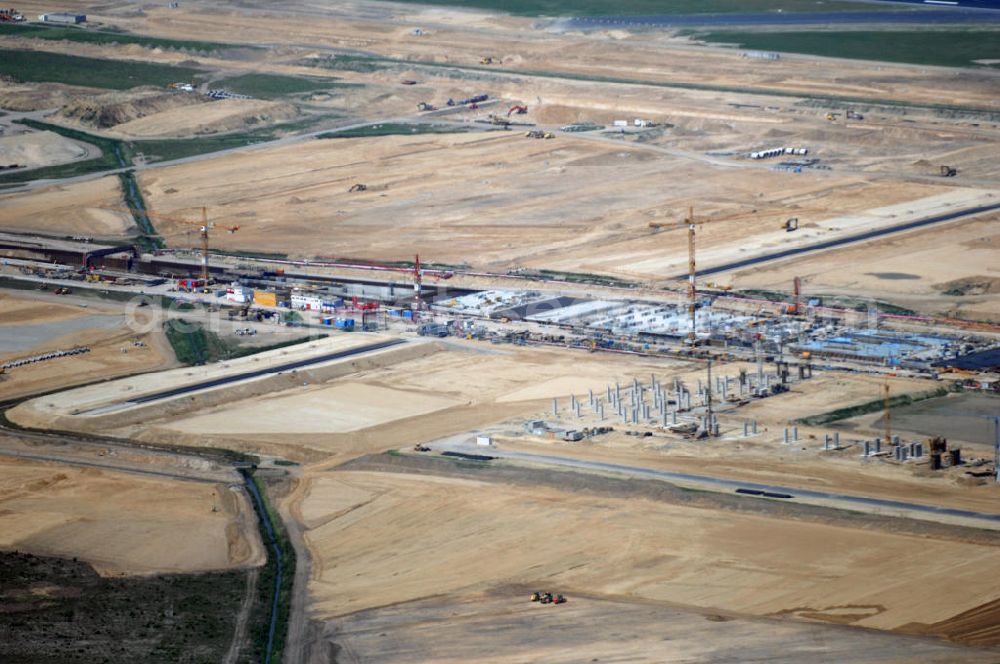 Aerial image Berllin - Blick auf den Ausbau des Flughafen Schönefeld zum neuen Flughafen Berlin-Brandenburg. Betreiber wird die Flughafen Berlin-Schönefeld GmbH (FBS) sein. Der erste Spatenstich erfolgte am 5. September 2006. BBI ist eines der größten im Bau befindlichen Verkehrsinfrastrukturprojekte Deutschlands. Kern des Neubaufeldes ist der Bahnhof, er bildet das Fundament für das noch zu errichtende Fluggast-Terminal. Über zwei Bahnsteige für Regional- und Fernverkehr sowie einen S-Bahnsteig können die Reisenden in Zukunft dann direkt den Flughafen erreichen. Wenn der neue Flughafen Berlin Brandenburg International (BBI) 2011 eröffnet wird, sollen es rund 22 Millionen Passagiere in Berlin werden. Ausbau der A113n als südöstliches Tor zur Hauptstadt. Unter Berücksichtigung des Flughafens Berlin Brandenburg International wurde eine Verkehrskonzeption für den Ausbau des Straßennetzes im Raum Berlin-Schönefeld erarbeitet, die zwei Stufen umfasste. Die erste Stufe sah den vierstreifigen Ausbau der Bundesstraßen B 96a und B 179 mit der Anbindung des Flughafens über zwei Knotenpunkte vor. Inhalt der zweiten Stufe war der Anschluß der Bundesautobahn A 113 neu an die B 96a und B 179. SCHÜßLER Plan Ingenieurgesellschaft, BATEG, EUROVIA, BERGER. Berliner Flughäfen: Ralf Kunkel, Tel. +49 (0)30 6091 2055, Fax +49 (0)30 6091 1643