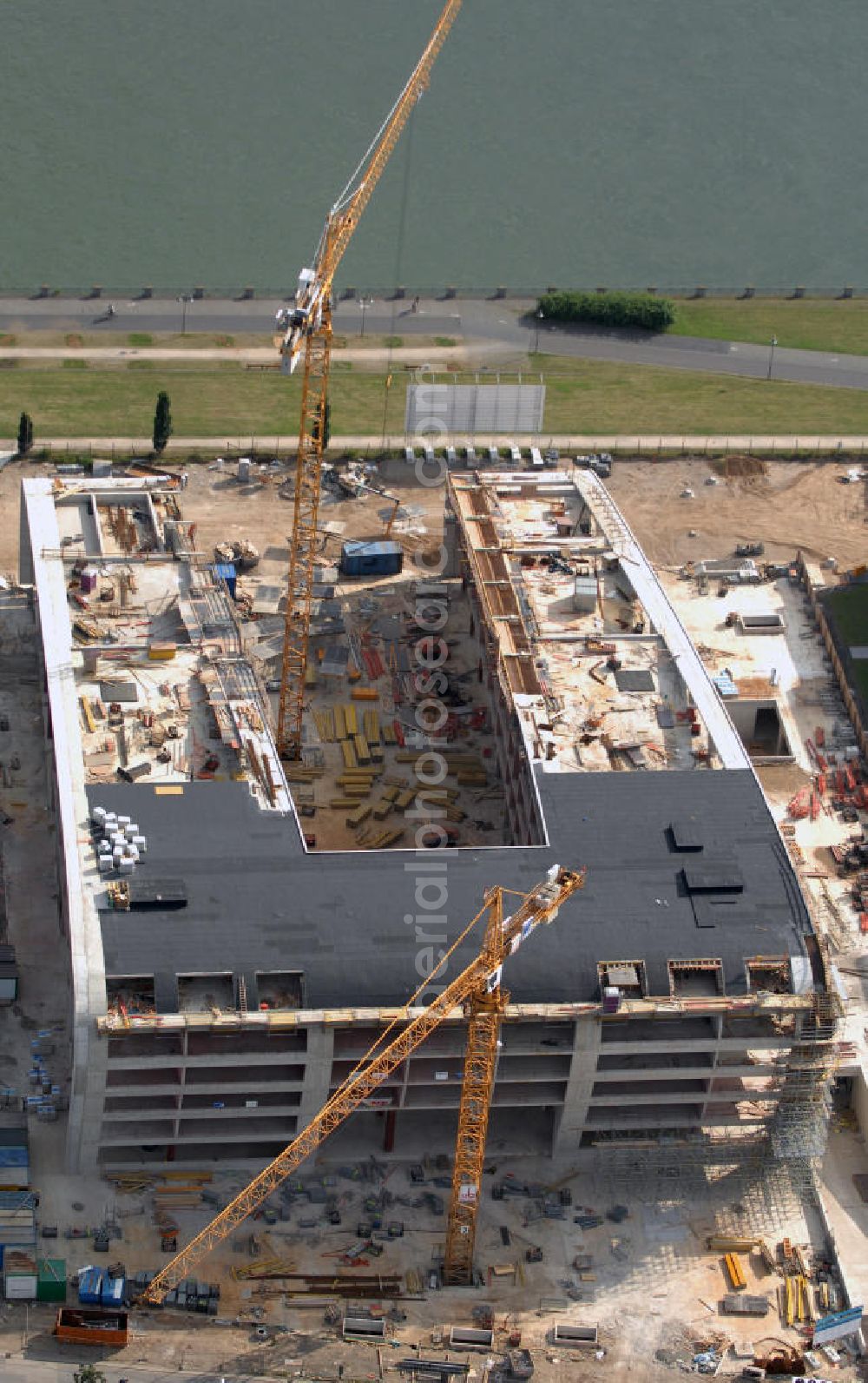 Bonn from above - Blick auf die Baustelle des Premium Hotels, das im Rahmen des Projekts Rheinwerk 2 gebaut wird. Es handelt sich um ein fünf Sterne Hotel mit Tagungs-, Konferenzräumen, sowie einer Eventhalle. Außerdem wird ein Restaurant inklusive Rheinbar und eine Rheinterrasse geben. Durch den vorhandenen Schiffsanleger kann man mit einem Wassertaxi direkt zur City oder auch zum UN Campus fahren. Bonn gilt als beliebter Standort für Industrie und so sind 45% der Büroräume schon vor Fertigstellung des Baus vermietet. Das Rheinwerk 2 wird aus vier Gebäudekörpern bestehen. Kontakt: Rheinwerk 2 GmbH, Dottendorfer Straße 64 53129 Bonn, Tel. +49(0)228 94928 0, Fax +49(0)228 94928 28, Mobil: +49(0)172 2406106, Email: info@rheinwerk2.de