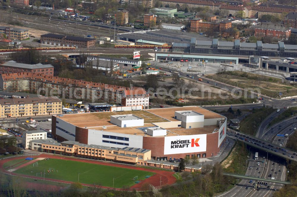 Aerial photograph Berlin - Blick auf die neue Filiale des Unternehmens Möbel Kraft über einen Sportplatz. Der Sportplatz wird bis 2009 für die Leichtathletik-Weltmeisterschaften als Trainigsstätte umgebaut. Das Möbelhaus besitzt eine eigene Autobahnabfahrt der A100 und verfügt über 40.0000 qm Verkaufsfläche auf 4 Etagen. Adresse: Sachsendamm 20, 10829 Berlin, Tel. +49 (0)30 76107 335