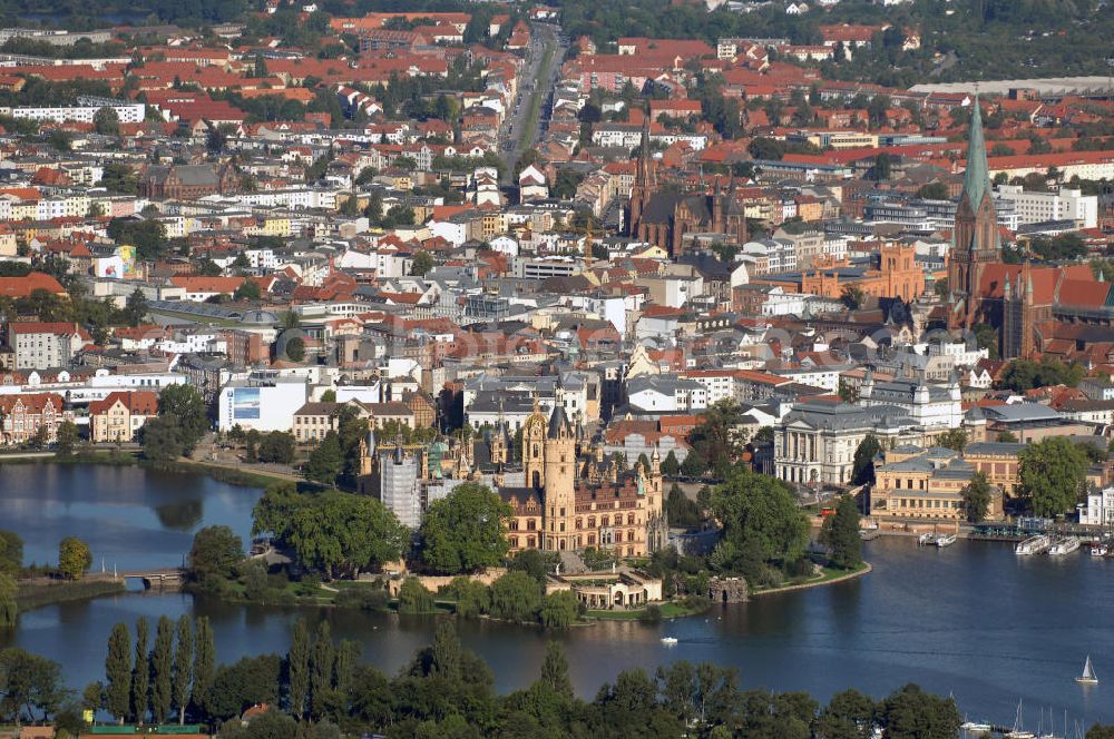 Aerial photograph SCHWERIN - Blick über das Schweriner Schloss auf die Altstadt Schwerin. Das Schloss liegt auf der Schlossinsel im Stadtzentrum von Schwerin. Das Schloss ist ein in einem 1000jährigen Prozess historisch gewachsenes Bauwerk, dessen Gestalt auf eine Wallanlage einer slawischen Burg zurückgeht, die um das Jahr 965 auf einer Insel im Schweriner See errichtet wurde. Das heutige Schloss, das als Schlüsselwerk für die Gestaltungsweise des romantischen Historismus gilt, entstand durch einen tiefgreifenden Um- und Neubau des alten Schlosses in den Jahren 1845 bis 1857. Es war für lange Zeit Residenz der mecklenburgischen Herzöge und Großherzöge. Seit 1990 ist es Sitz des Landtages des Bundeslandes Mecklenburg-Vorpommern. Der als Museum genutzte Teil gehört zum Staatlichen Museum Schwerin. Kontakt: Landeshauptstadt Schwerin, Presse, Mareike Wolf, Am Packhof 2-6, 19053 Schwerin, Fax +49 (0)385 545 1019, Tel. +49 (0)385 545 1013, EMail mwolf@schwerin.de