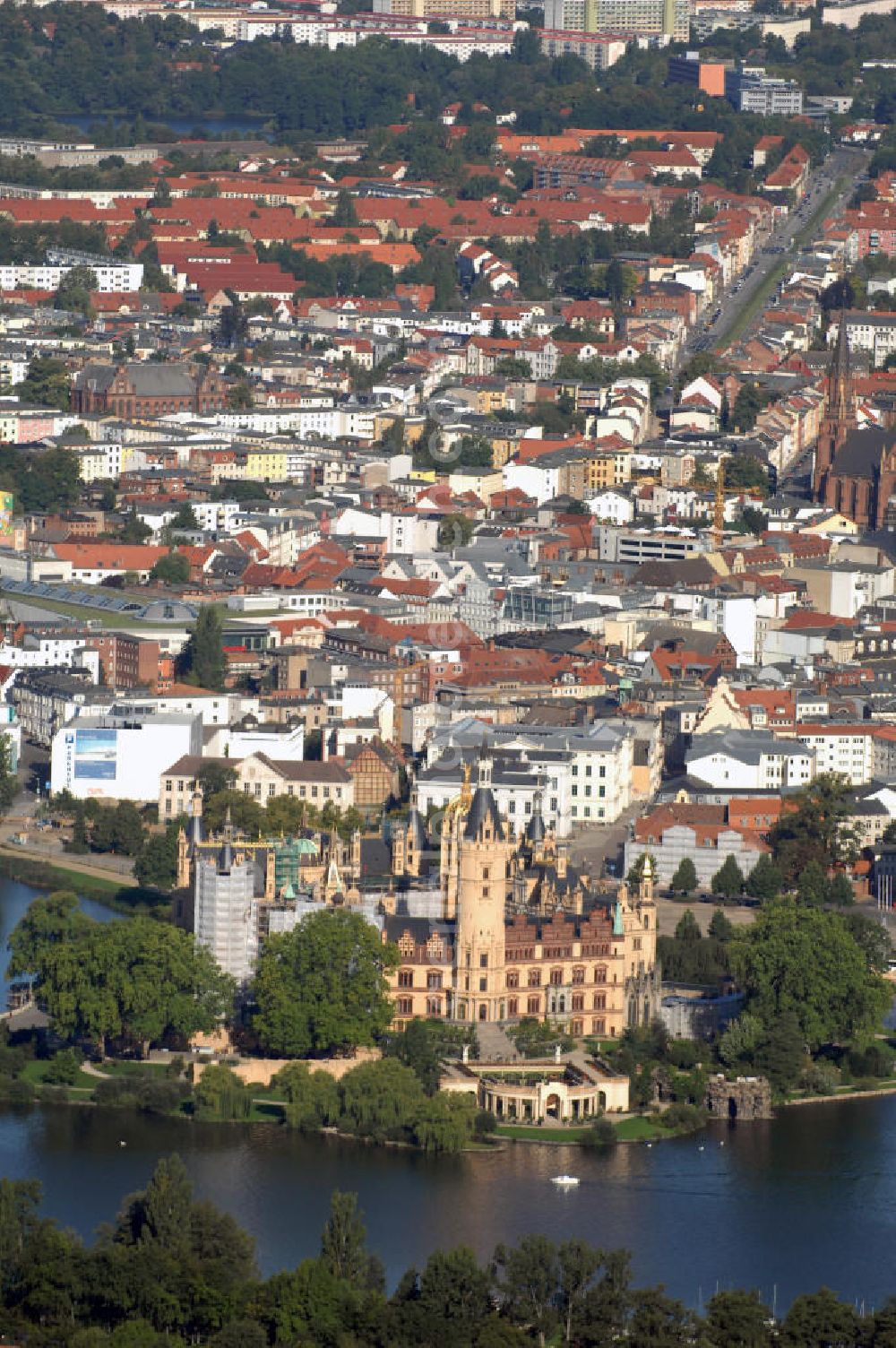 SCHWERIN from above - Blick über das Schweriner Schloss auf die Altstadt Schwerin. Das Schloss liegt auf der Schlossinsel im Stadtzentrum von Schwerin. Das Schloss ist ein in einem 1000jährigen Prozess historisch gewachsenes Bauwerk, dessen Gestalt auf eine Wallanlage einer slawischen Burg zurückgeht, die um das Jahr 965 auf einer Insel im Schweriner See errichtet wurde. Das heutige Schloss, das als Schlüsselwerk für die Gestaltungsweise des romantischen Historismus gilt, entstand durch einen tiefgreifenden Um- und Neubau des alten Schlosses in den Jahren 1845 bis 1857. Es war für lange Zeit Residenz der mecklenburgischen Herzöge und Großherzöge. Seit 1990 ist es Sitz des Landtages des Bundeslandes Mecklenburg-Vorpommern. Der als Museum genutzte Teil gehört zum Staatlichen Museum Schwerin. Kontakt: Landeshauptstadt Schwerin, Presse, Mareike Wolf, Am Packhof 2-6, 19053 Schwerin, Fax +49 (0)385 545 1019, Tel. +49 (0)385 545 1013, EMail mwolf@schwerin.de