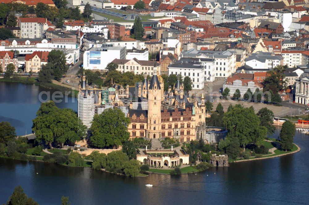 SCHWERIN from the bird's eye view: Blick über das Schweriner Schloss auf die Altstadt Schwerin. Das Schloss liegt auf der Schlossinsel im Stadtzentrum von Schwerin. Das Schloss ist ein in einem 1000jährigen Prozess historisch gewachsenes Bauwerk, dessen Gestalt auf eine Wallanlage einer slawischen Burg zurückgeht, die um das Jahr 965 auf einer Insel im Schweriner See errichtet wurde. Das heutige Schloss, das als Schlüsselwerk für die Gestaltungsweise des romantischen Historismus gilt, entstand durch einen tiefgreifenden Um- und Neubau des alten Schlosses in den Jahren 1845 bis 1857. Es war für lange Zeit Residenz der mecklenburgischen Herzöge und Großherzöge. Seit 1990 ist es Sitz des Landtages des Bundeslandes Mecklenburg-Vorpommern. Der als Museum genutzte Teil gehört zum Staatlichen Museum Schwerin. Kontakt: Landeshauptstadt Schwerin, Presse, Mareike Wolf, Am Packhof 2-6, 19053 Schwerin, Fax +49 (0)385 545 1019, Tel. +49 (0)385 545 1013, EMail mwolf@schwerin.de