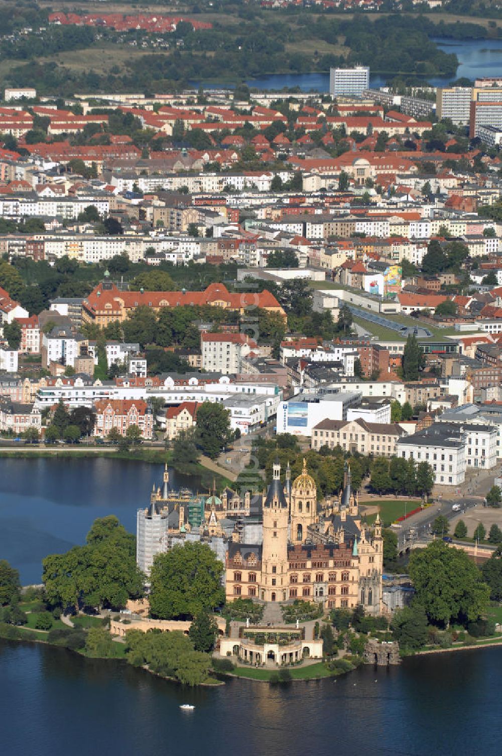 Aerial image SCHWERIN - Blick über das Schweriner Schloss auf die Altstadt Schwerin. Das Schloss liegt auf der Schlossinsel im Stadtzentrum von Schwerin. Das Schloss ist ein in einem 1000jährigen Prozess historisch gewachsenes Bauwerk, dessen Gestalt auf eine Wallanlage einer slawischen Burg zurückgeht, die um das Jahr 965 auf einer Insel im Schweriner See errichtet wurde. Das heutige Schloss, das als Schlüsselwerk für die Gestaltungsweise des romantischen Historismus gilt, entstand durch einen tiefgreifenden Um- und Neubau des alten Schlosses in den Jahren 1845 bis 1857. Es war für lange Zeit Residenz der mecklenburgischen Herzöge und Großherzöge. Seit 1990 ist es Sitz des Landtages des Bundeslandes Mecklenburg-Vorpommern. Der als Museum genutzte Teil gehört zum Staatlichen Museum Schwerin. Kontakt: Landeshauptstadt Schwerin, Presse, Mareike Wolf, Am Packhof 2-6, 19053 Schwerin, Fax +49 (0)385 545 1019, Tel. +49 (0)385 545 1013, EMail mwolf@schwerin.de