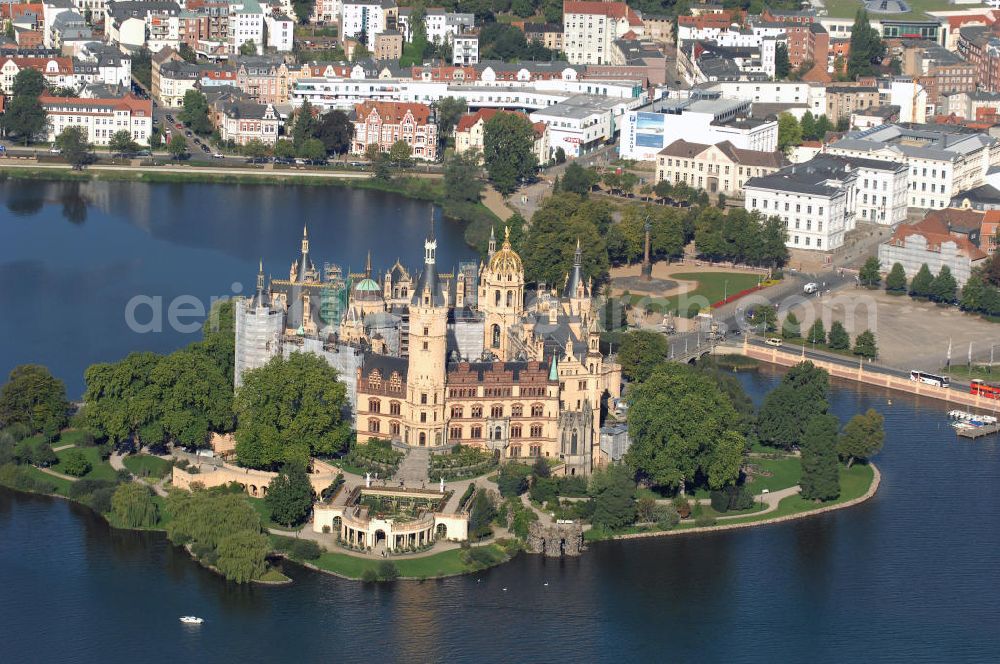 Aerial photograph SCHWERIN - Blick über das Schweriner Schloss auf die Altstadt Schwerin. Das Schloss liegt auf der Schlossinsel im Stadtzentrum von Schwerin. Das Schloss ist ein in einem 1000jährigen Prozess historisch gewachsenes Bauwerk, dessen Gestalt auf eine Wallanlage einer slawischen Burg zurückgeht, die um das Jahr 965 auf einer Insel im Schweriner See errichtet wurde. Das heutige Schloss, das als Schlüsselwerk für die Gestaltungsweise des romantischen Historismus gilt, entstand durch einen tiefgreifenden Um- und Neubau des alten Schlosses in den Jahren 1845 bis 1857. Es war für lange Zeit Residenz der mecklenburgischen Herzöge und Großherzöge. Seit 1990 ist es Sitz des Landtages des Bundeslandes Mecklenburg-Vorpommern. Der als Museum genutzte Teil gehört zum Staatlichen Museum Schwerin. Kontakt: Landeshauptstadt Schwerin, Presse, Mareike Wolf, Am Packhof 2-6, 19053 Schwerin, Fax +49 (0)385 545 1019, Tel. +49 (0)385 545 1013, EMail mwolf@schwerin.de