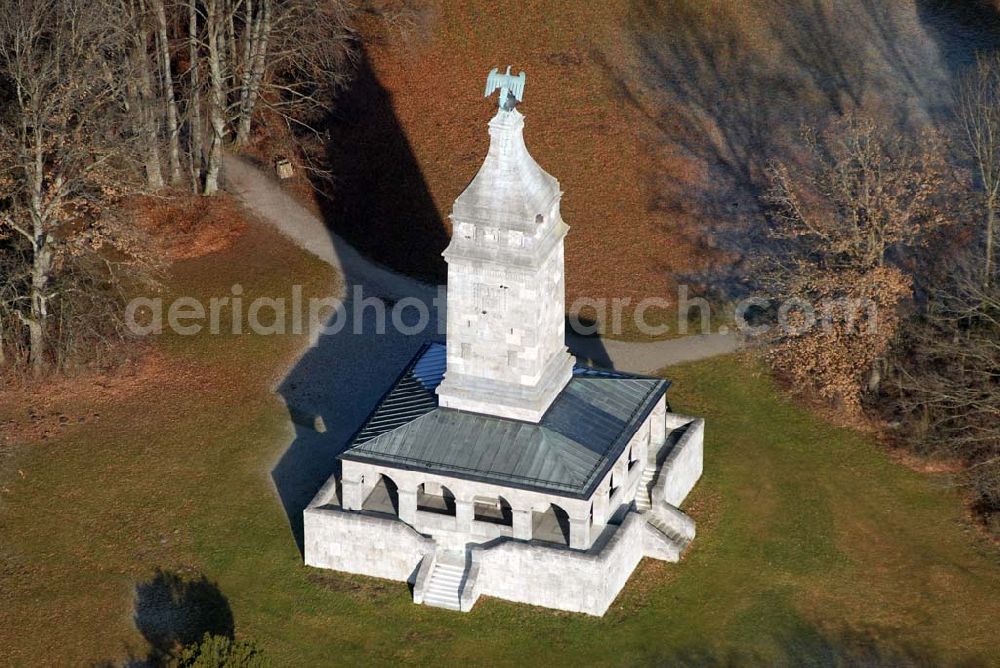 Assenhausen from the bird's eye view: Blick auf den Bismarckturm in Assenhausen am Starnberger See. Im Jahre 1890 wurde in München unter dem Vorsitz des Malers Prof. Dr. Franz von Lenbach und Bürgermeister Dr. von Widenmayer ein Komitee zur Errichtung einer Bismarcksäule gegründet. Die Einweihung des 30 m hohen Ehrenturmes fand am 01.07.1899 statt. Der Bismarck-Verein schenkte das Denkmal (mit 9,172 Hektar großem Grundstück) der Stadt München. Um den quadratischen Sockel des Turmes läuft eine mit 16 offenen Rundbögen gebildete Wandelhalle. Von allen vier Seiten führen Treppen zur Wandelhalle. In der Halle sind Wappenschilde der Bundesstaaten und freien Städte, an der Nordseite eine Bismarck-Widmungstafel mit den Portraitköpfen Karls des Großen, Friedrich Barbarossas, Ottos des Großen, Goethes, Dürers und Beethovens (Vorbilder Bismarcks) angebracht. Der Turm ist bekrönt von einem kupfernen Adler (hergestellt von Kiehne). Als Material für den Turm wurden Kalkstein und Tuff verwendet. Die künstlerische Gestaltung (außen und innen) oblag den Bildhauern H. Flossmann und Georg Wrba. Die Bronzetafel mit Bismarckwappen und Reichsadlerrelief (s. Foto oben mitte) wurde von der Erzgießerei Renaissance (Johann Lampel) hergestellt.