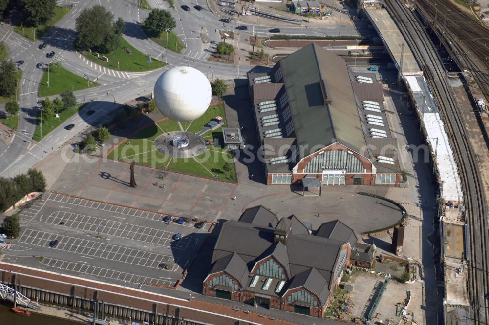 Hamburg from above - Blick auf die Deichtorhallen und den Highflyer Fesselballon in Hamburg. Die Deichtorhallen sind Europas größte Kunstausstellungshallen und gliedern sich in das Haus der Photographie und eine zweite Ausstellungshalle für aktuelle Kunst. Hier finden nicht nur Ausstellungen schon großer und namhafter Künstler statt, auch junge noch unbekannte Künstler bekommen immer wieder die Möglichkeit ihre Werke in einem recht großen Rahmen auszustellen. Neben den Ausstellungsräumen gibt es auch einen Design- und Buchshop der Photographie, sowie ein Restaurant. Zwischen den beiden Gebäuden der Deichtorhallen befindet sich eine weitere Touristenattraktion, der Highflyer Fesselballon. Er ist fest installiert und an einem 180 Meter langen Drahtseil befestigt um immer wieder an der gleichen Stellen landen zu können. Mit ihm können 30 Personen in die Luft steigen und die Aussicht auf und über Hamburg genießen. Kontakt: Deichtorhallen Hamburg GmbH, Deichtorstraße 1-2 20095 Hamburg, Tel. +49(0)40 3210 30, Fax +49(0)40 3210 3230, Email: mail@deichtorhallen.de