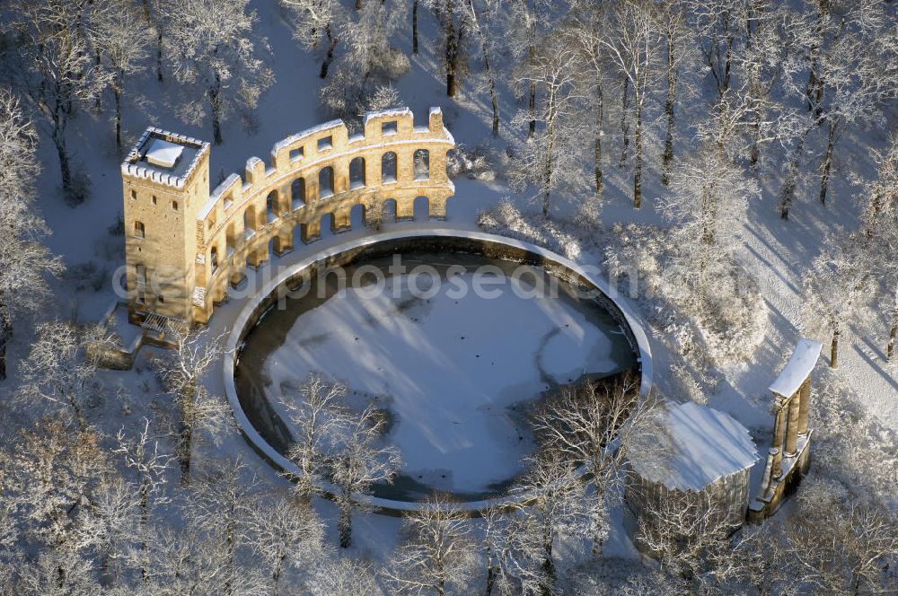 POTSDAM from above - Blick auf den winterlich verschneiten Ruinenberg, einer Anhöhe zwischen Potsdam-Bornstedt im Westen und der Potsdamer Jägervorstadt im Osten. Zur Bewässerung der Fontänen im südlich angrenzenden Park Sanssouci ließ Friedrich der Große 1748 auf der Kuppe ein Wasserreservoir bauen und mit künstlichen Ruinen als antikisierende Gestaltungselemente ausschmücken. Im Zuge der Landschaftsverschönerung um Potsdam beauftragte Friedrich Wilhelm IV. den Gartenarchitekten Peter Joseph Lenné 1841 mit der gärtnerischen Gestaltung des Ruinenberggeländes.