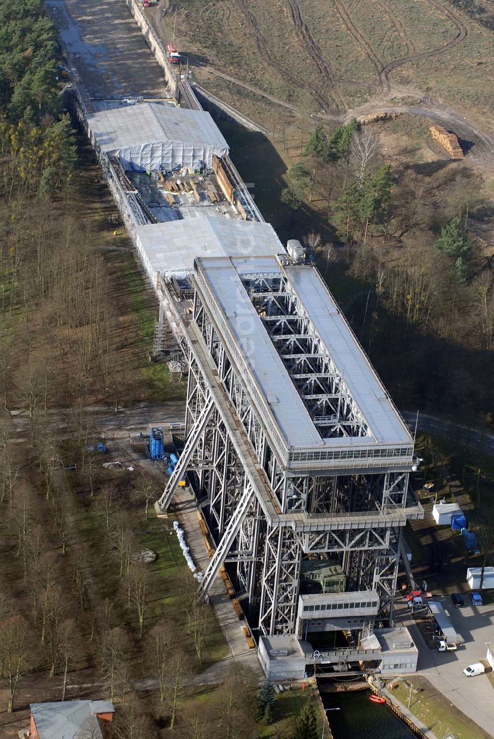 Niederfinow from above - Blick auf derzeitige Wartungsarbeiten am Schiffshebewerk Niederfinow mit trockengelegter Kanalbrücke. Das Schiffshebewerk an der Oder-Havel-Wasserstraße ist wegenWartungsarbeiten gesperrt worden. Dieses Jahr dauert die Sperrung bis zum 31. März und damit zwölf statt sechs Wochen, da der Korrosionsschutz an der Kanalbrücke erneuert werden muss. Die Arbeiten finden in 40 Metern Höhe statt und kosten 3,1 Millionen Euro. Der Schiffsfahrstuhl gilt als Engpass auf dem Wasserweg zwischen Berlin und dem Ostseehafen Stettin (Szczecin). Darum ist ein Neubau in Planung, der in voraussichtlich fünf Jahren fertig gestellt sein wird. Das alte Schiffshebewerk hat noch eine so genannte nominale Restnutzungsdauer bis zum Jahr 2025 und bleibt nach dem Neubau des Schiffshebewerkes Niederfinow Nord betriebsbereit erhalten. Das Schiffshebewerk zieht jährlich zwischen 200 000 und 300 000 Besucher an.