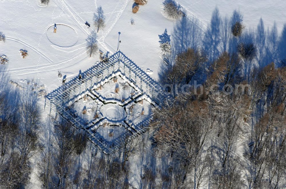 Aerial image Berlin - Blick auf den Garten des wiedergewonnenen Mondes im winterlich verschneiten Chinesischen Garten im Erholungspark Marzahn. Der Erholungspark Marzahn liegt im Berliner Bezirk Marzahn-Hellersdorf am nördlichen Fuß des Kienbergs und wurde am 9. Mai 1987 anlässlich der 750-Jahr-Feier von Berlin als Berliner Gartenschau und Geschenk der Gärtner an die Hauptstadt der DDR (Ost-Berlin) eröffnet und sollte somit ein Gegenstück zum Britzer Garten im damaligen West-Berlin darstellen. 1991 wurde die Berliner Gartenschau nicht nur in Erholungspark Marzahn umbenannt, sondern auch umgebaut: Große Spiel- und Liegewiesen sowie neue Spielplätze entstanden, Bäume wurden gepflanzt und Sondergärten überarbeitet und erweitert. Der neu gestaltete Park sollte den 300.000 Bewohnern der umliegenden Großsiedlungen als vielfältig nutzbare Erholungslandschaft dienen. Seit Oktober 2000 ist diese durch ihre Gärten der Welt auch weit über die Stadtgrenzen hinaus bekannt. 2005 wurde der Chinesische Garten im Erholungspark Marzahn als drittschönste Parkanlage Deutschlands ausgezeichnet. Außerdem gehört der Erholungspark zu den 365 Orten im Land der Ideen.