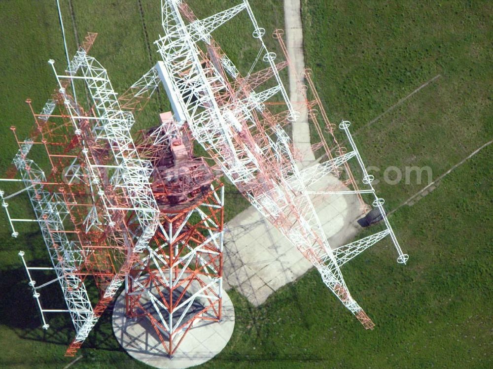 Aerial image Nauen - Blick auf das Gelände der historische Sendestelle Nauen. Von hier wurde schon seit 1906 weltweit gesendet. Uebliche Sendefrequenzen lagen bei 20-100 kHz. Antennenlaenge 2,4 km. Modulation in Morsezeichen. Nauen sendete und empfing u.a. Telegramme. In Geltow bei Potsdam wurde eine Empfangs-Station gebaut (30 km von Nauen entfernt). Hier stoerten die starken Sende-Signale nicht den Funkempfang. In Nauen wurden Knallfunkensender, Loeschfunkensender, Hochfrequenz-Maschinen und Roehrensender eingesetzt. Eine der korrespondierenden Stationen in den USA war Long Island bei New York. 1920 wurde das neue Sende-Gebäude (von Herman Muthesius) eingeweiht. Die Transradio Gesellschaft fuehrte weltweiten Funkbetrieb durch. Gesendet wurde Hochgeschwindigkeits-Morse- Code. Telegramme konnten auch in Bueros in Berlin und an deren Staedten aufgegeben werden. Auch Zeitzeichen wurden gesendet. Ab 1940 wurde auch Rundfunk gesendet. Ab 1957 sendete aus benachbarten Gebaeuden Radio Berlin International, Deutscher demokratischer Rundfunk. Seit 1990 ist die Deutsche Welle aktiv. 1997 wurden 4 neue KW-Sender mit jeweils 500 kW in Betrieb genommen. Sender und Antenne bilden eine Einheit (Foto eines der vier Senderaeume ). Die alten KW-Sender aus DDR-Zeit sind noch im Reserve-Betrieb. Die alte Dreh-Antenne war weltweit bekannt. Ein Teil der alten Antennen-Anlage ist 1999 abgerissen worden.