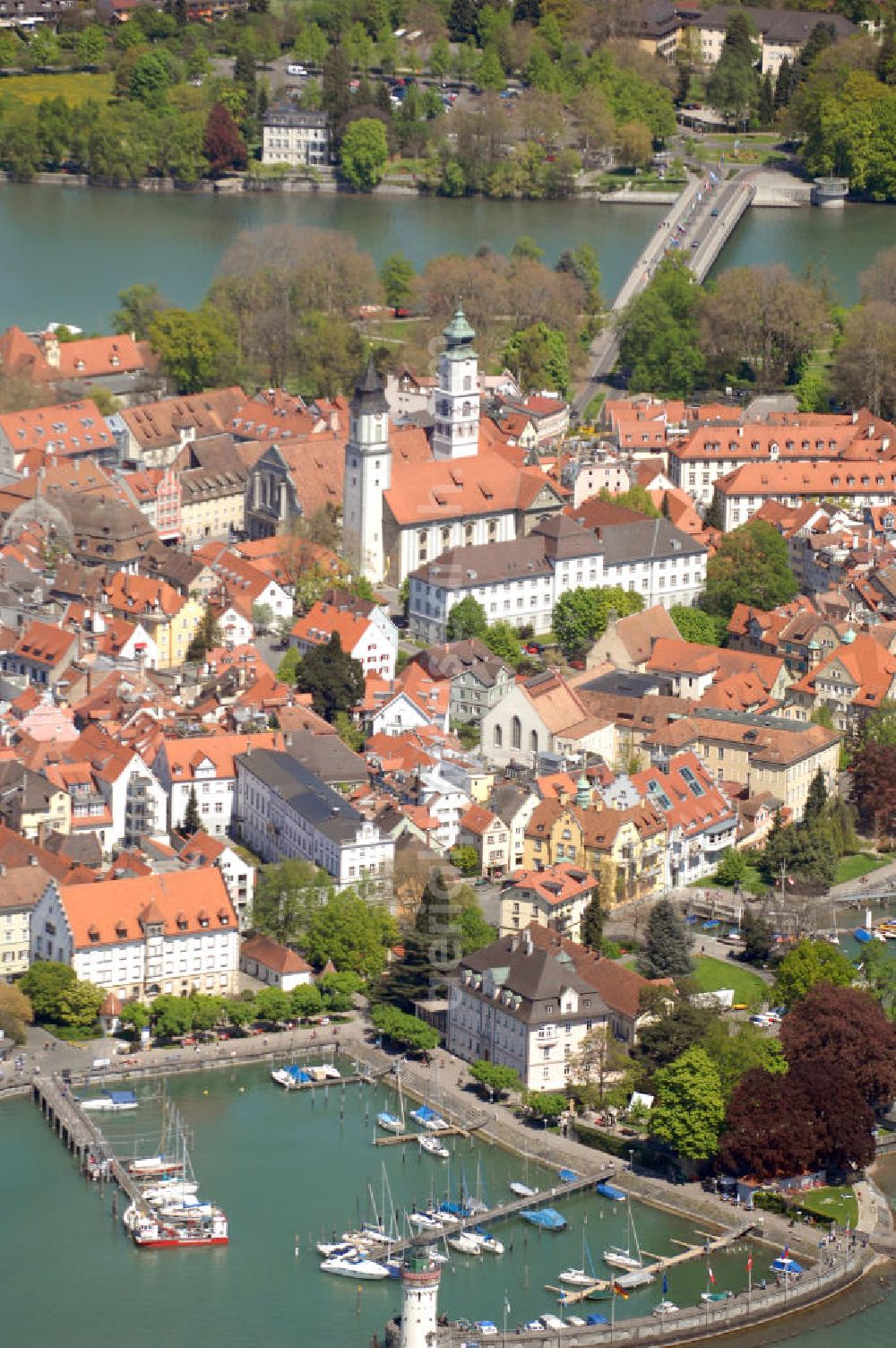 Aerial photograph Lindau - Blick auf die Lindau Insel mit Hafen, Mangturm und Altstadt. Die Hafeneinfahrt an der Lindau Insel ist von einem Leuchtturm und dem Bayerischen Löwen begrenzt. Der Mangturm wurde um 1200 als Leuchtturm erbaut und war der Turm der ehemaligen Stadtbefestigung. Als besonderer Hingucker dient hier das bunte Dach, welches aus dem 19. Jhd. stammt. Seinen Namen hat er durch das ehemalige Tuch- und Manghaus, dass sich dort in der Nähe befand. Kontakt: Tourist-Information, Ludwigstraße 68, 88131 Lindau, Tel.: +49(0)8382 2600 30, Fax: +49(0)8382 2600 26, E-Mail: info@prolindau.de